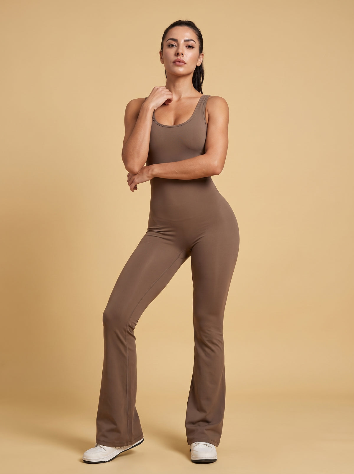 Modelka w szarobrązowym kombinezonie Flame pozuje przodem w studio
